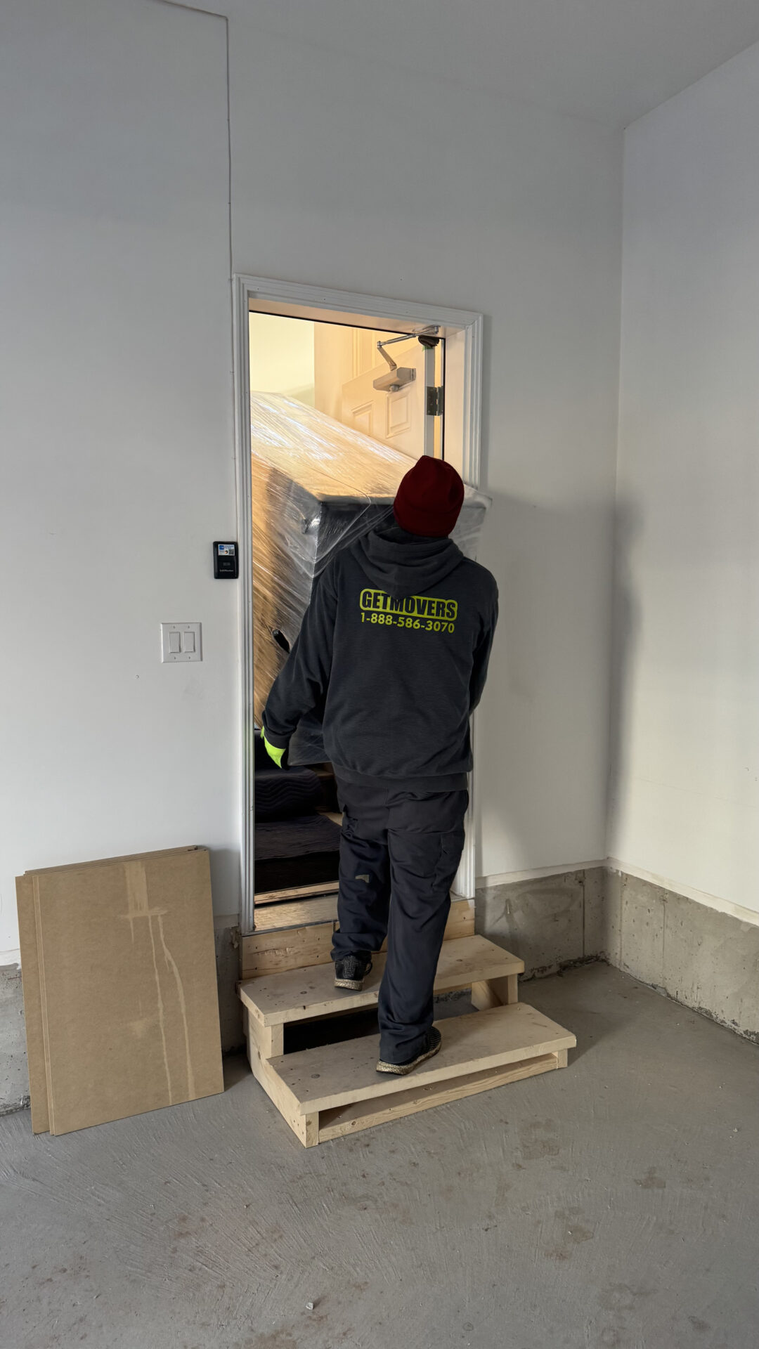 Tall wooden shelving unit wrapped and moved through a tight hallway.