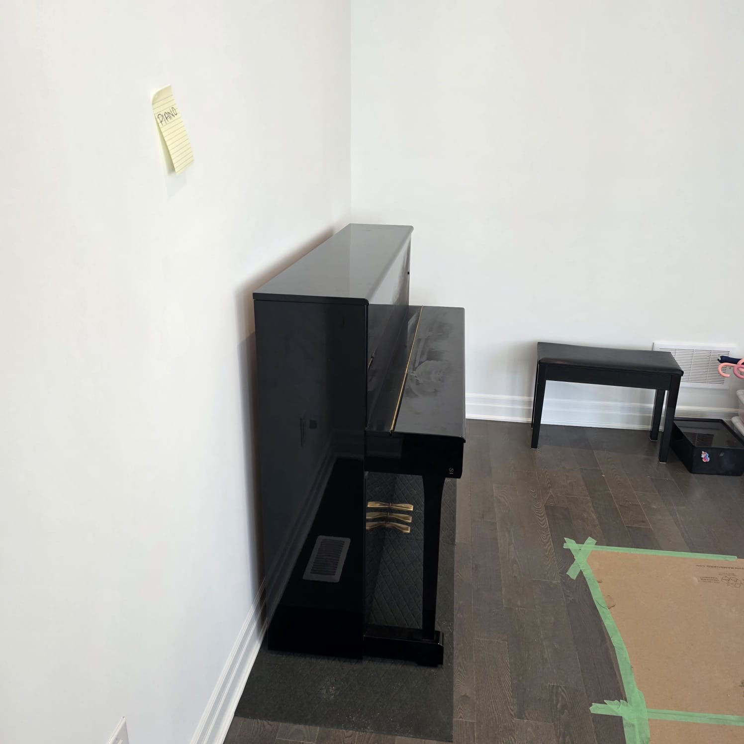 Movers wrapping a bookcase with protective pads in a hallway.