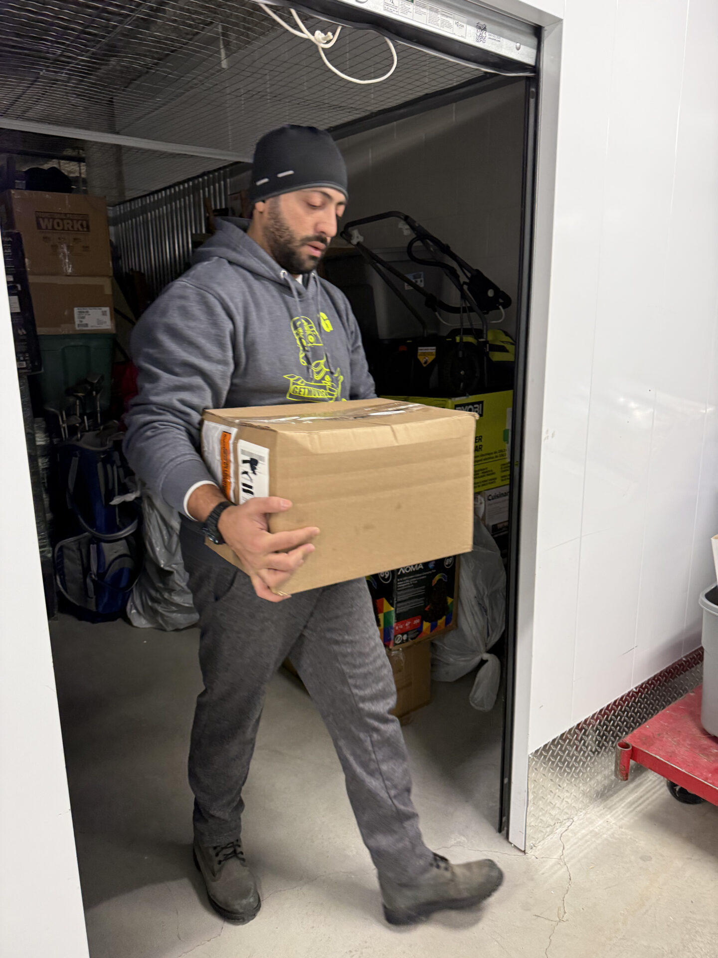 Movers navigating a snowy walkway with protected furniture.