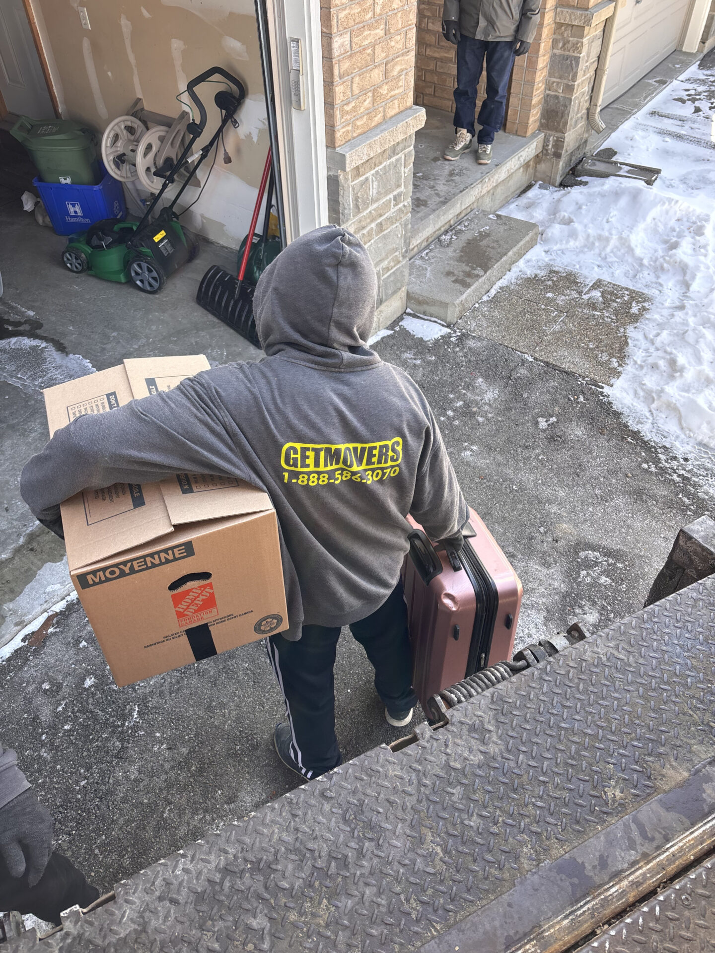 Movers navigating a narrow hallway with a wrapped furniture piece.