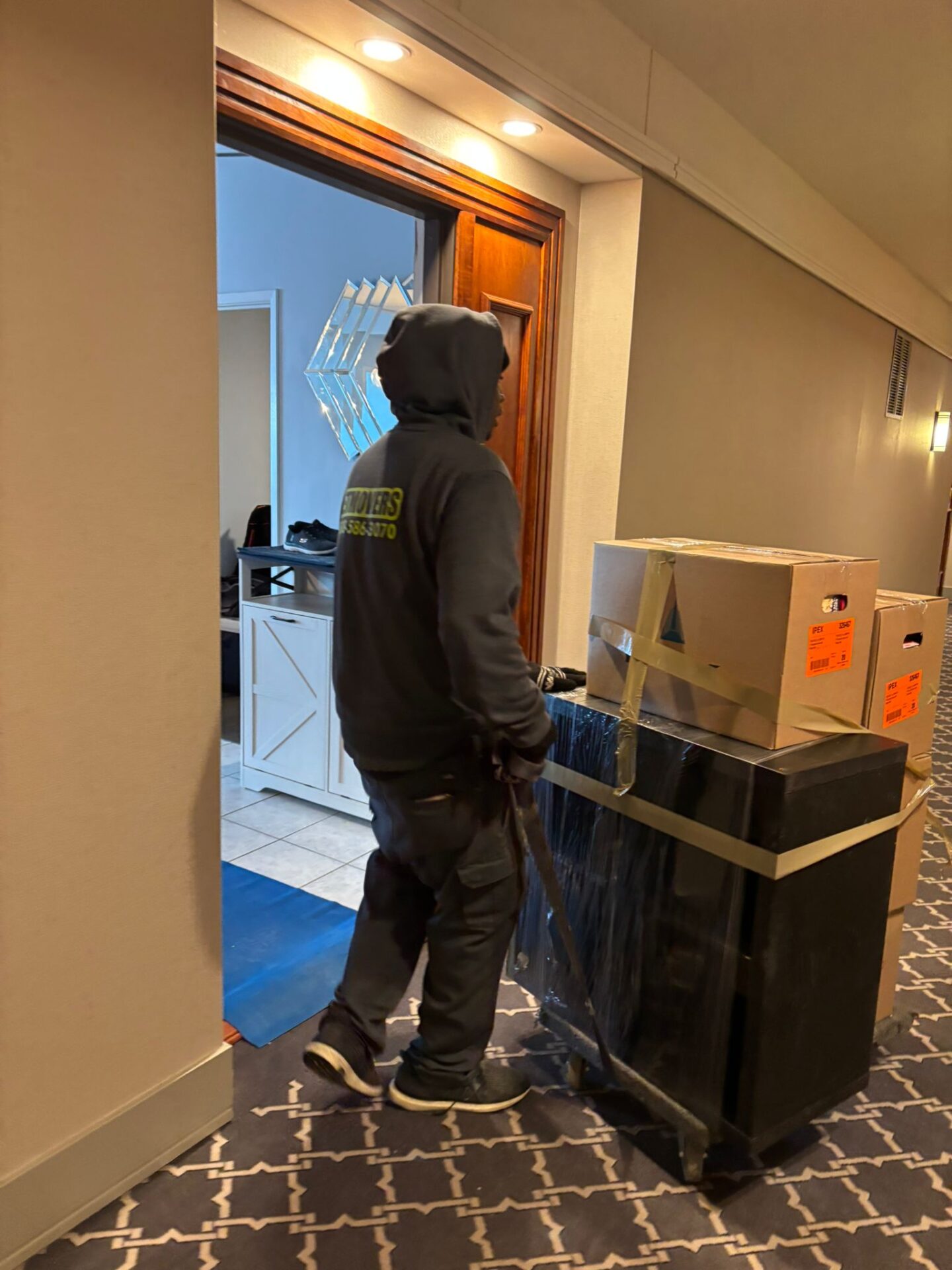 Movers navigating tight spaces with a tall wooden cabinet.